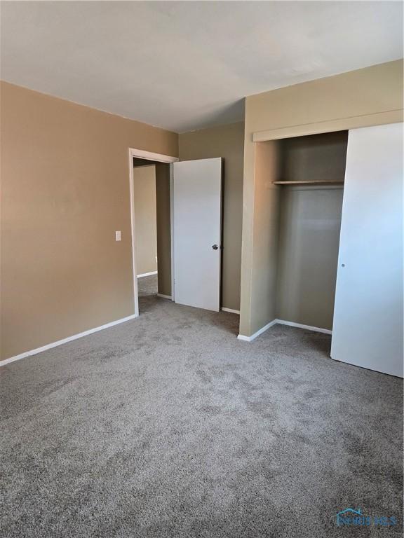 unfurnished bedroom with a closet, carpet flooring, and baseboards