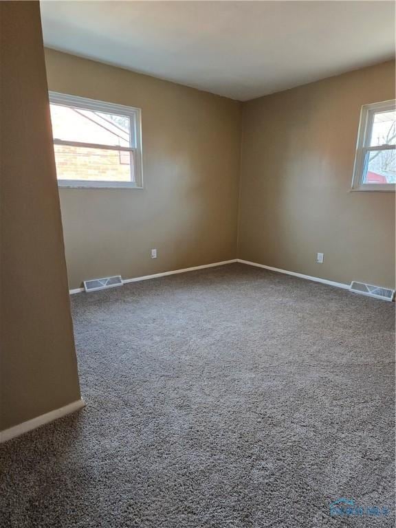 spare room with carpet, visible vents, and baseboards