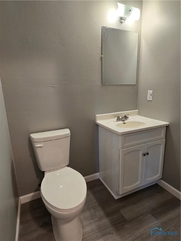 bathroom with baseboards, toilet, wood finished floors, and vanity