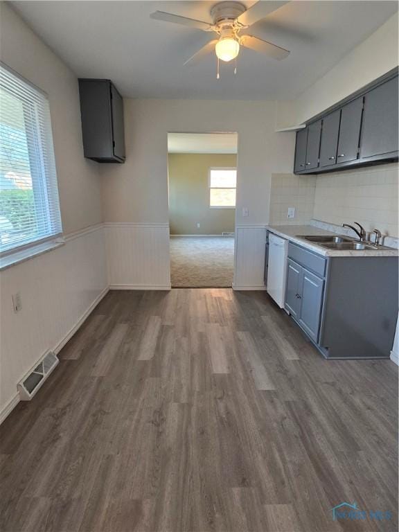 kitchen featuring visible vents, dark wood finished floors, dishwasher, gray cabinets, and a sink