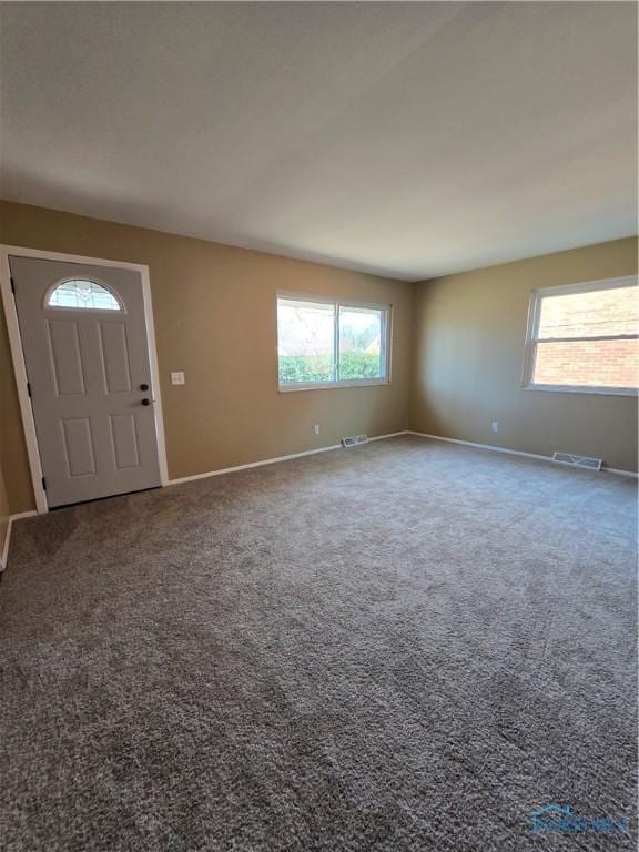 entryway featuring plenty of natural light, carpet, visible vents, and baseboards