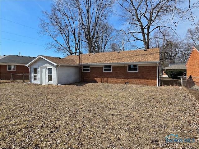 back of property featuring fence, brick siding, roof with shingles, and crawl space