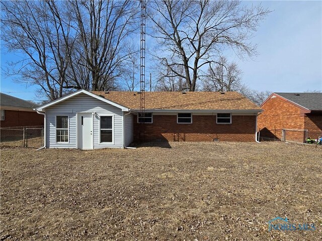 back of house featuring a gate, fence, roof with shingles, crawl space, and brick siding