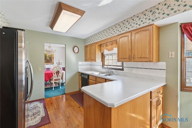 kitchen with a sink, light wood-style flooring, light countertops, and freestanding refrigerator