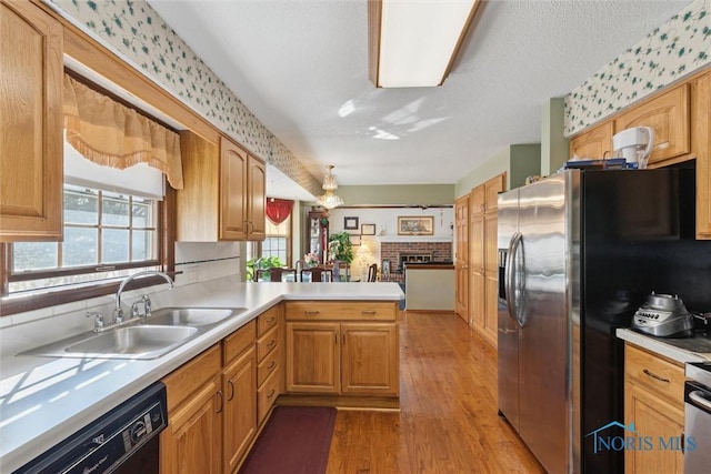 kitchen featuring wallpapered walls, a peninsula, stainless steel fridge with ice dispenser, a sink, and black dishwasher