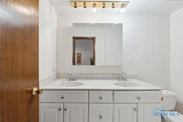 bathroom with a sink, toilet, and double vanity