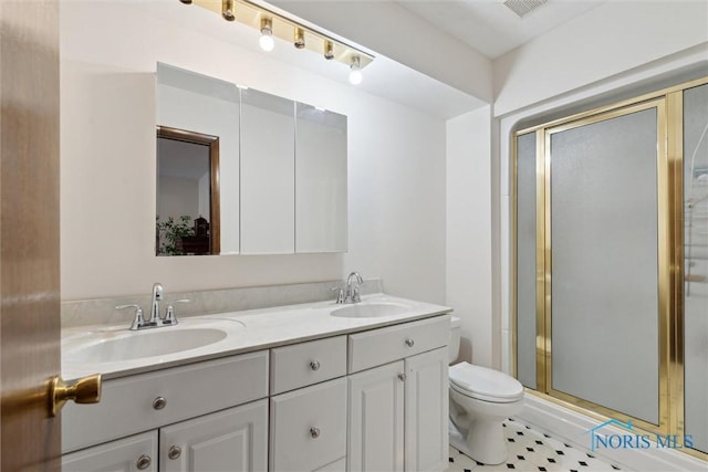 full bathroom with double vanity, a shower stall, toilet, and a sink