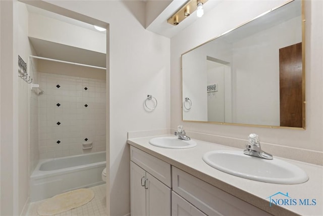 full bath with double vanity, toilet, shower / bathing tub combination, and a sink