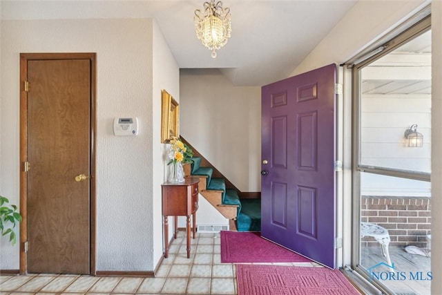 entrance foyer featuring visible vents, baseboards, a chandelier, and stairs