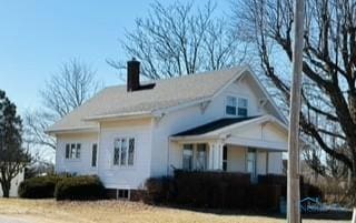 view of side of home with covered porch and a chimney