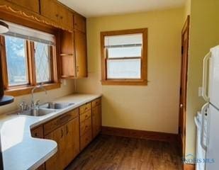 kitchen with dark wood finished floors, light countertops, brown cabinetry, and a sink