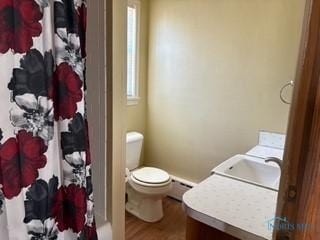 full bathroom with vanity, a shower with shower curtain, wood finished floors, toilet, and baseboard heating