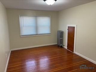 empty room featuring radiator, baseboards, and wood finished floors