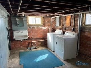 laundry area featuring a sink, brick wall, laundry area, and washing machine and clothes dryer