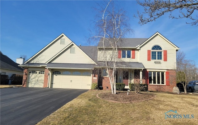 traditional-style house with brick siding, driveway, an attached garage, and a front yard