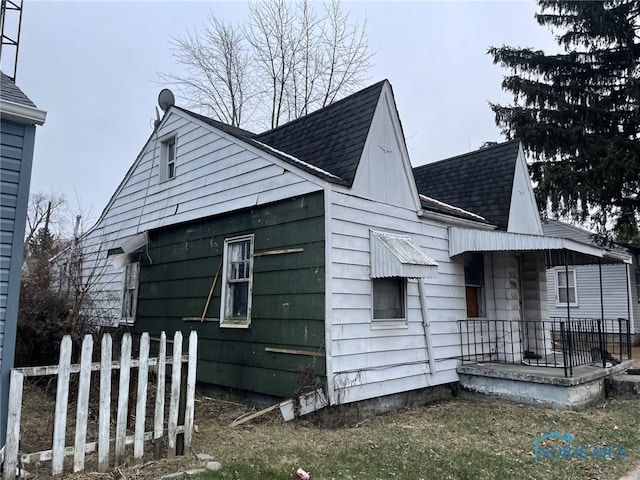 view of property exterior with a shingled roof and fence