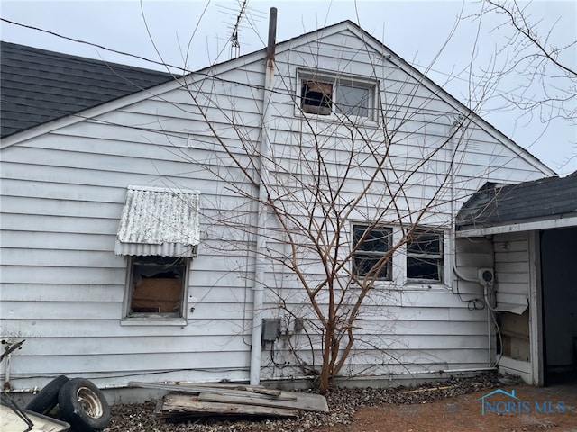 view of side of home with roof with shingles