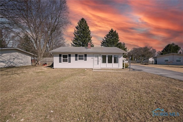 view of front of house with a chimney, a front yard, and fence