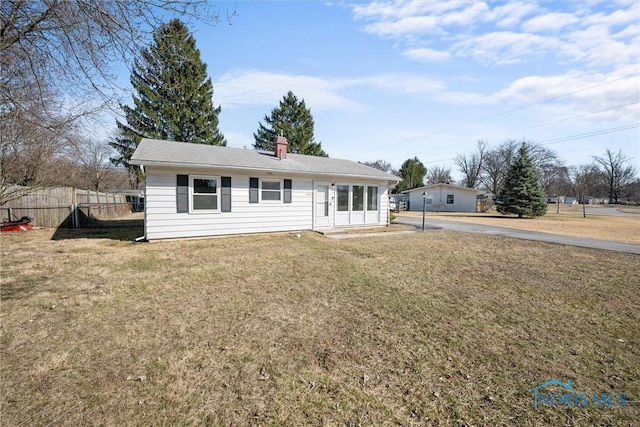 ranch-style house featuring a chimney, a front lawn, and fence