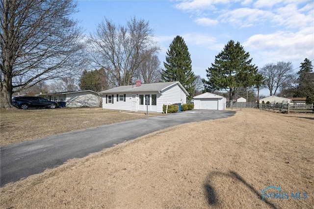 single story home with fence, a chimney, an outdoor structure, a front lawn, and a garage