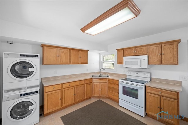 kitchen with stacked washer and dryer, a sink, white appliances, light countertops, and light tile patterned floors