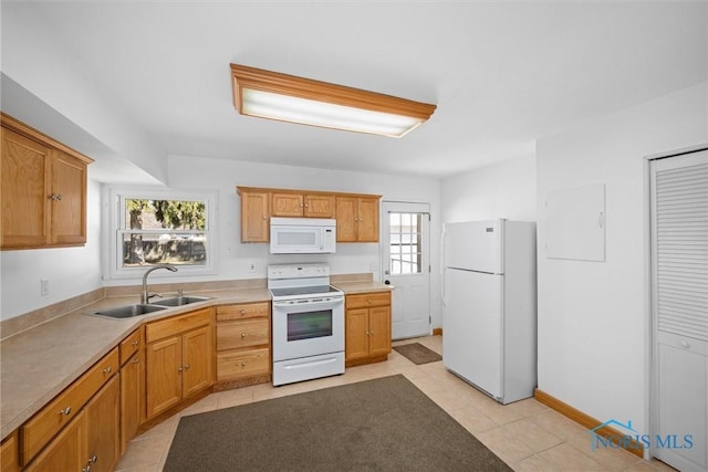 kitchen with baseboards, light countertops, light tile patterned floors, white appliances, and a sink