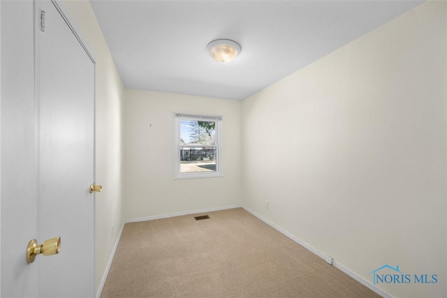 spare room with light carpet, visible vents, and baseboards