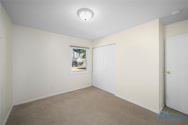 unfurnished bedroom with a closet, baseboards, and carpet