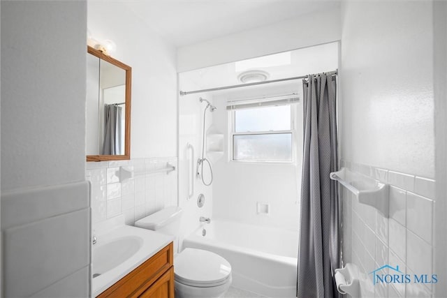 bathroom featuring tile walls, toilet, shower / tub combo with curtain, wainscoting, and vanity