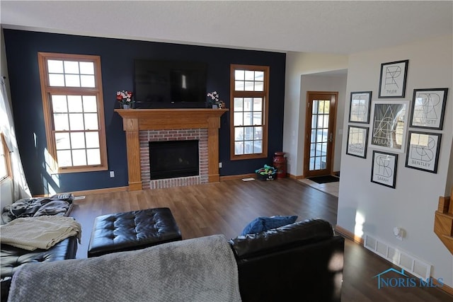 living area featuring visible vents, baseboards, wood finished floors, and a fireplace