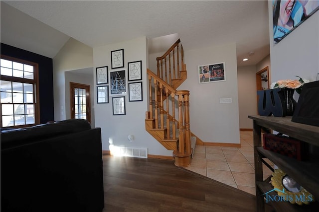 interior space featuring visible vents, lofted ceiling, tile patterned flooring, baseboards, and stairs