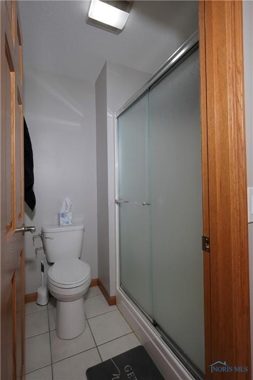 bathroom with tile patterned floors, baseboards, toilet, and a shower stall