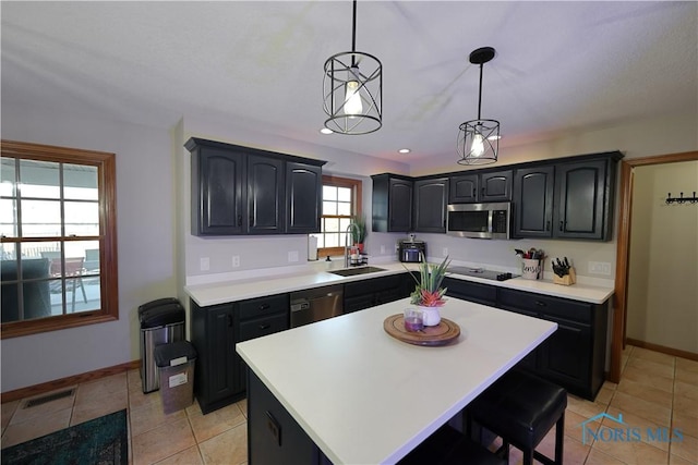 kitchen with visible vents, a kitchen island, stainless steel appliances, a sink, and light countertops