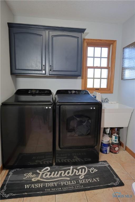 laundry area featuring tile patterned floors, cabinet space, and separate washer and dryer