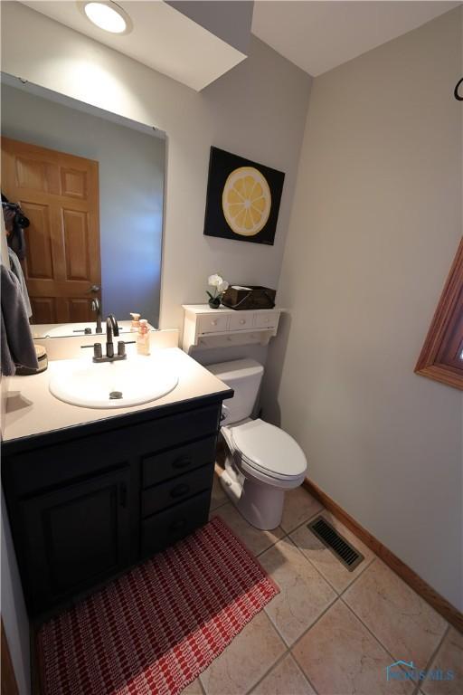 half bath featuring visible vents, baseboards, toilet, tile patterned floors, and vanity