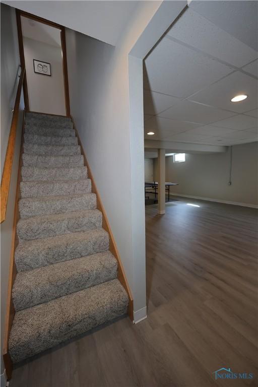 stairs with recessed lighting, wood finished floors, baseboards, and a paneled ceiling