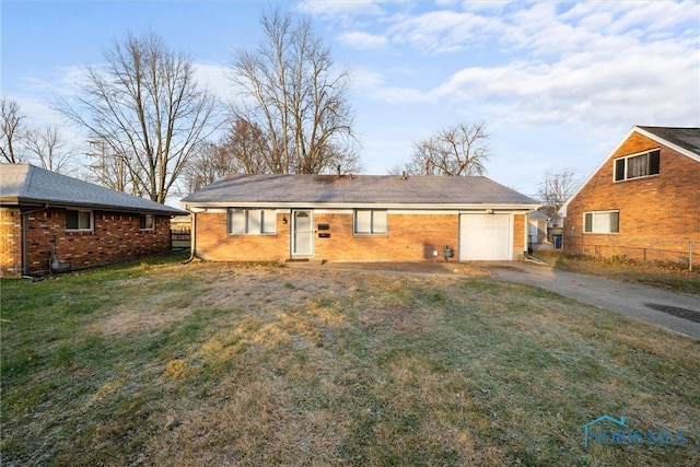 rear view of house with a lawn, driveway, fence, an attached garage, and brick siding