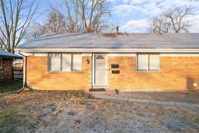 single story home featuring brick siding and a shingled roof