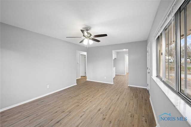 empty room with wood finished floors, baseboards, and ceiling fan