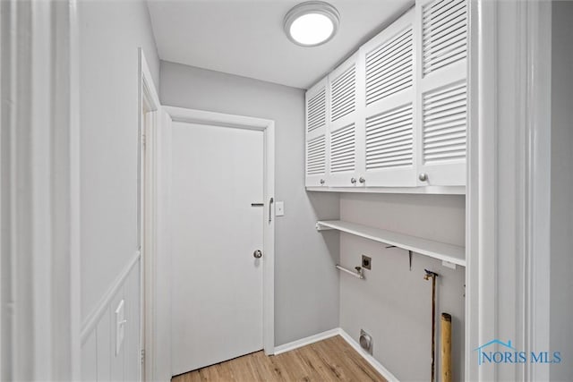 laundry room with electric dryer hookup, cabinet space, light wood-type flooring, and baseboards