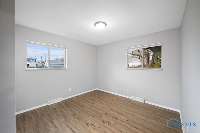 unfurnished room with visible vents, baseboards, and wood finished floors