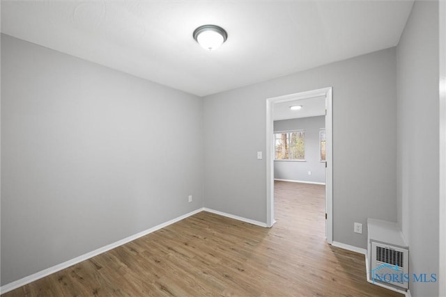 unfurnished room featuring visible vents, baseboards, and wood finished floors