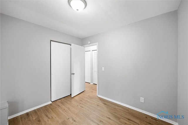 unfurnished bedroom featuring a closet, baseboards, and light wood-style floors