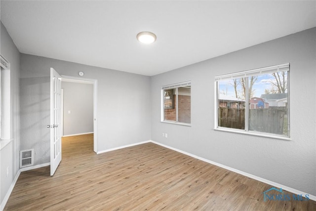 spare room featuring visible vents, light wood-type flooring, and baseboards