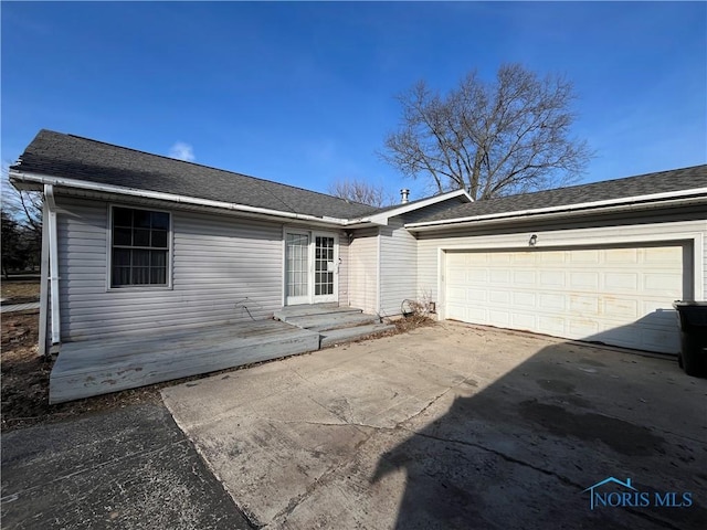 view of front facade with driveway, a garage, and roof with shingles