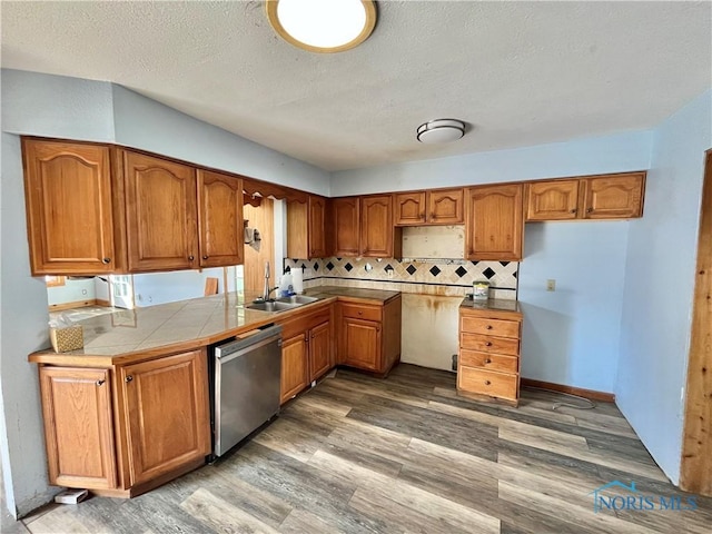 kitchen featuring a sink, light wood-style floors, stainless steel dishwasher, and brown cabinetry