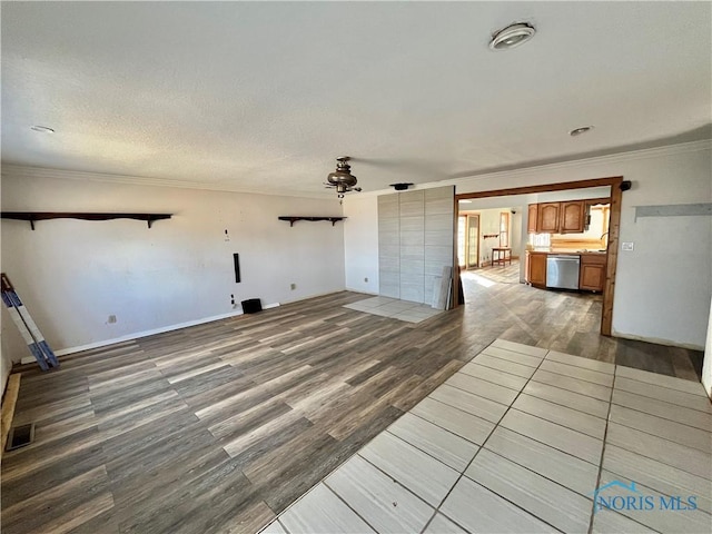 unfurnished living room featuring visible vents, ornamental molding, a textured ceiling, wood finished floors, and baseboards