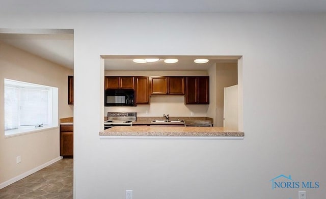 kitchen featuring baseboards, electric range oven, a sink, light countertops, and black microwave