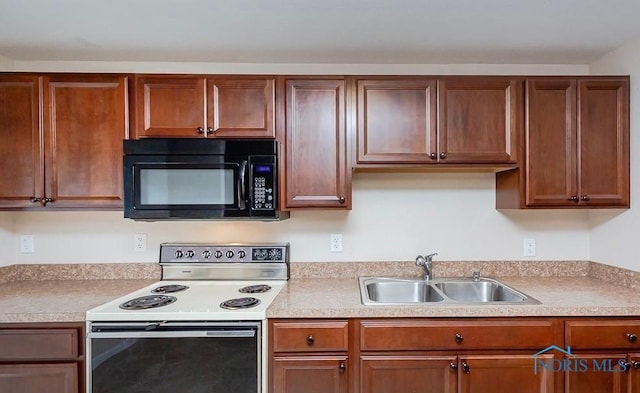 kitchen with electric range, light countertops, black microwave, and a sink