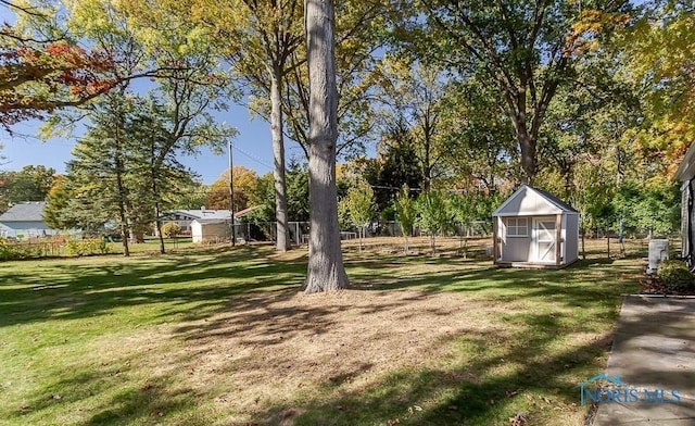 view of yard featuring a storage shed, an outdoor structure, and fence